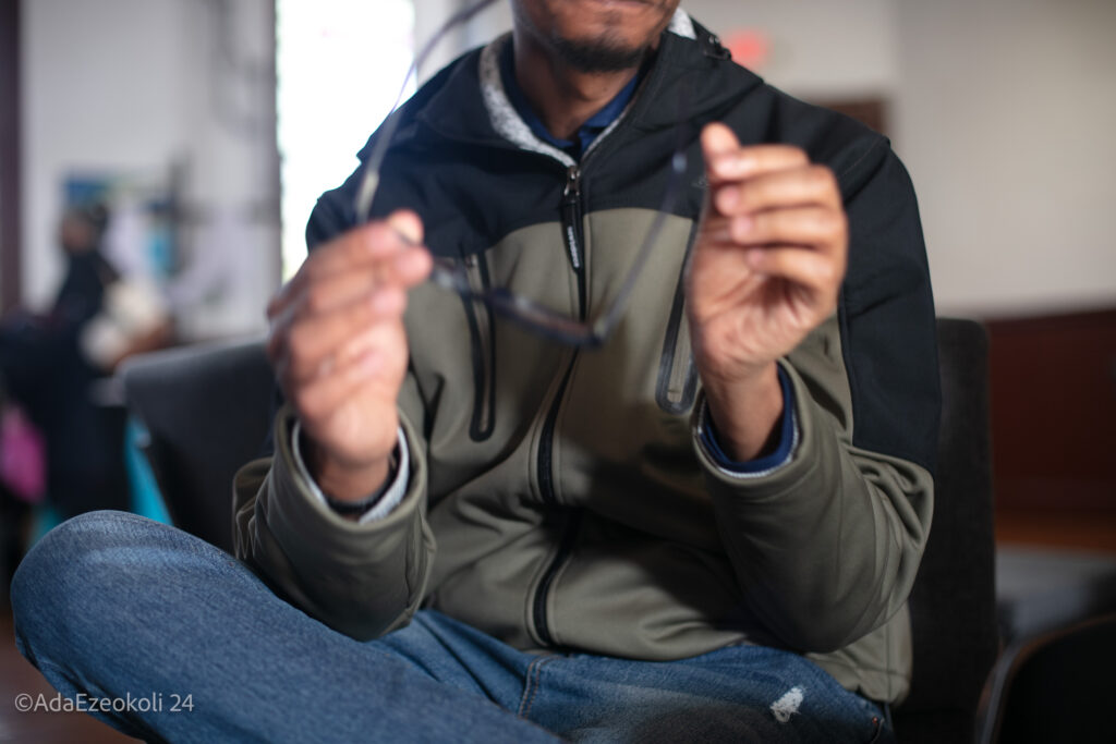 A young black man holding a pair of glasses