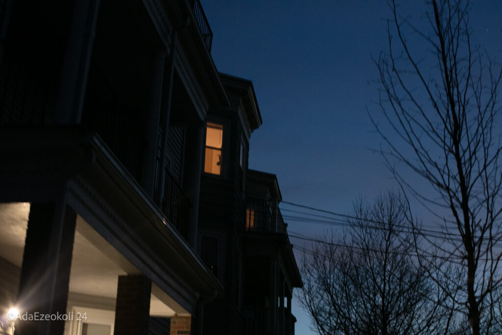 A lighted upstairs window in the dusk