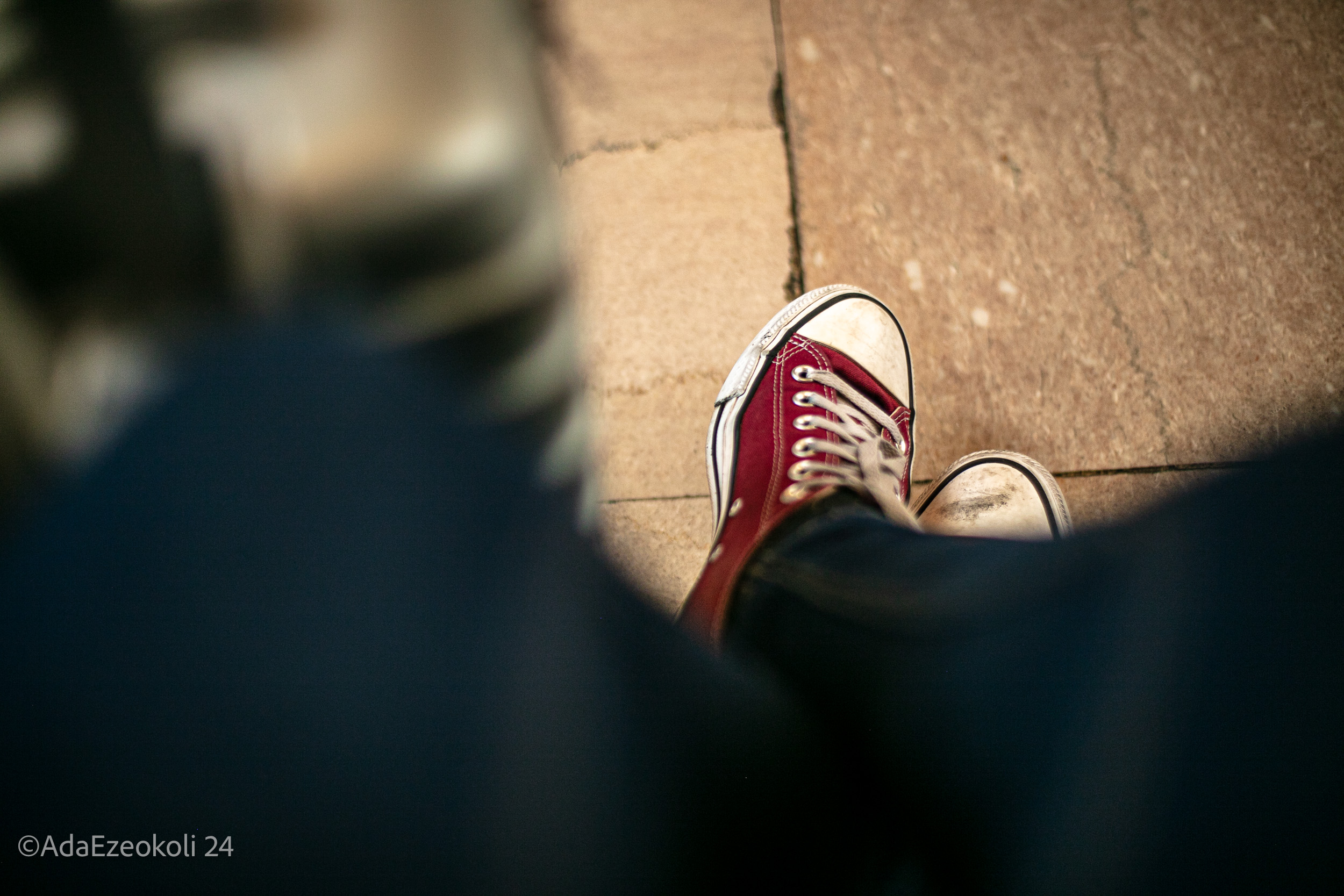 Crossed feet wearing red converse shoes