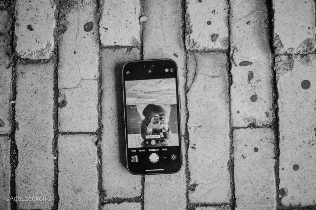 A woman takes a photo of herself on her cell phone using her camera