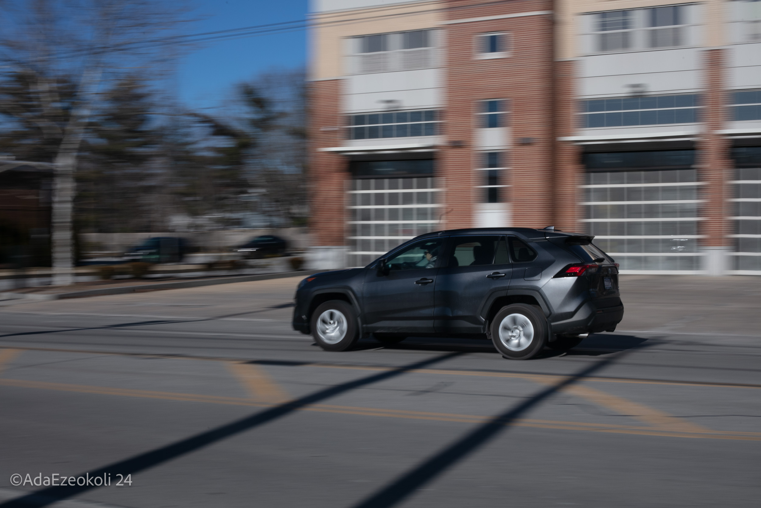 gray sedan driving past a building