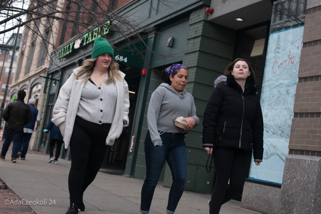 Three young ladies stroll down a sidewalk in Central Cambridge