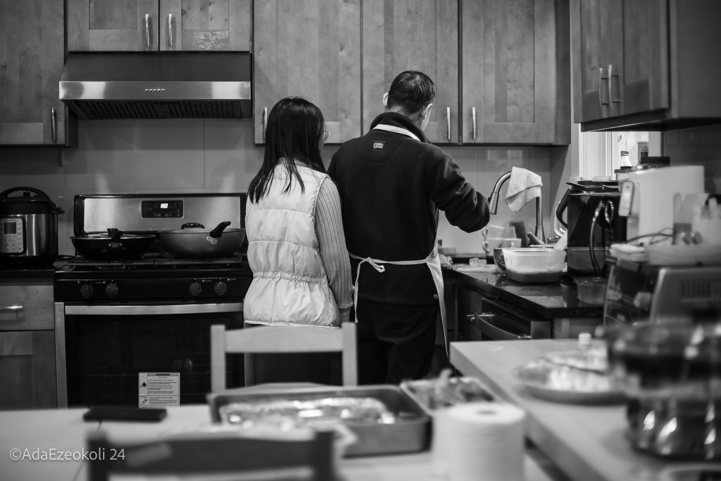 An Asian man and his daughter cooking together in a kitchen