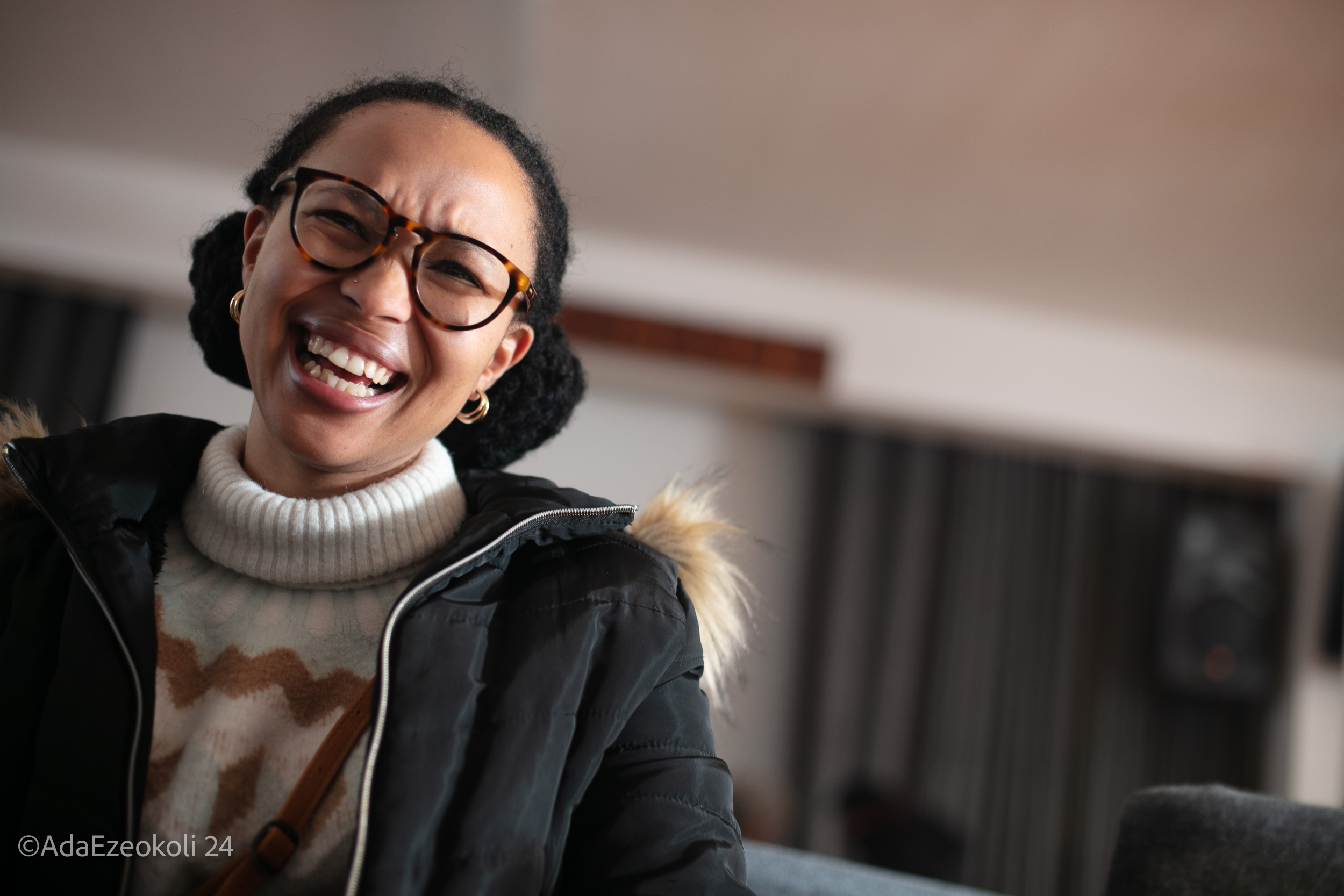 A young black woman wearing glasses and laughing